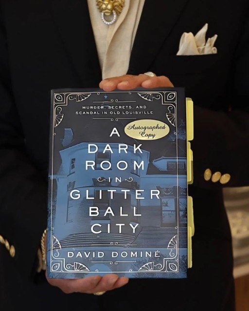 John holding his autographed copy of A Dark Room in Glitter Ball City by David Domin&eacute;
